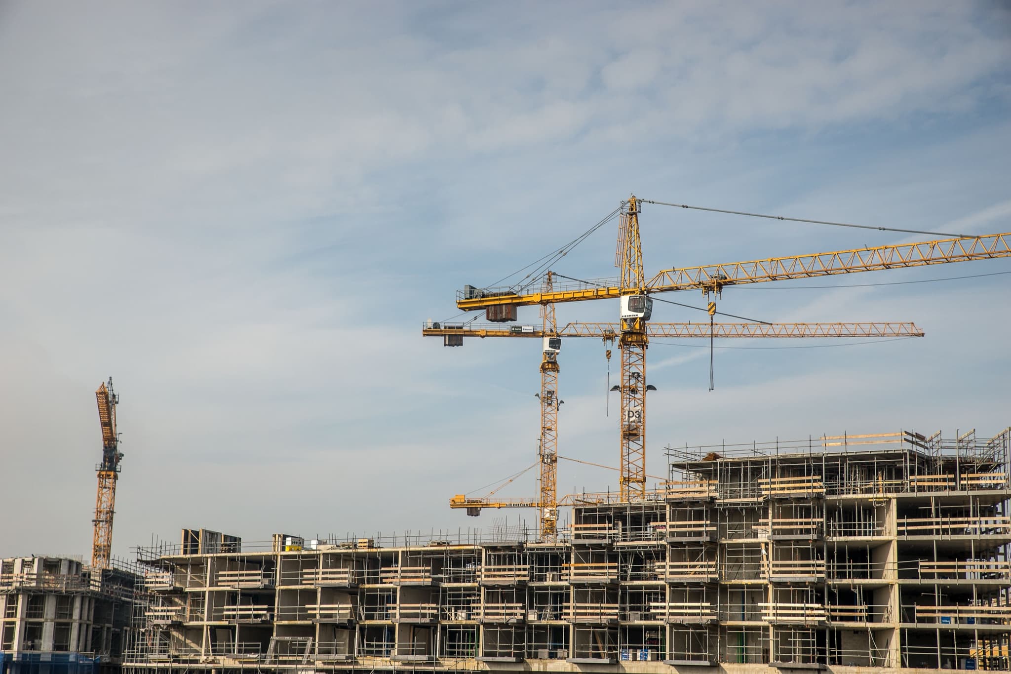 Tower cranes rising above a multi-storey concrete frame under construction